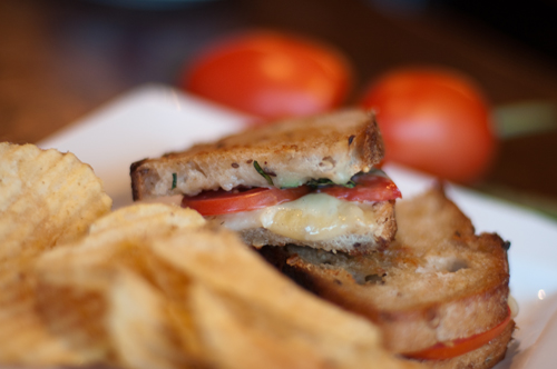 grilled cheese sandwich on plate with tomato and basil